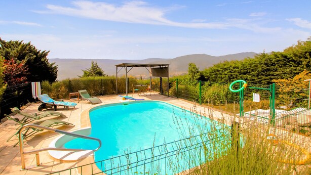 A swimming pool with lounge chairs and a covered seating area, surrounded by greenery and mountains in the background. - Gorgeous home in Veyras (Veyras)