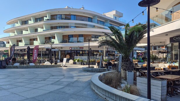 Un edificio moderno con varios balcones y un espacio central abierto con asientos al aire libre.