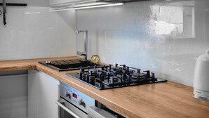 Una cocina moderna con extractor de acero inoxidable, un reloj digital y una estufa a gas.