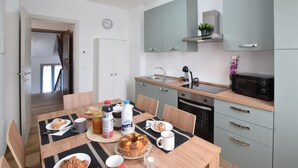 A modern kitchen with grey cabinets, a built-in oven, and a microwave. There is a dining table with breakfast items and a clock on the wall. - Awesome home in Marciano della Chiana (Marciano della Chiana)