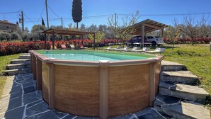 A hot tub with a wooden exterior, surrounded by stone steps and a garden with red flowers. - Awesome home in Marciano della Chiana (Marciano della Chiana)