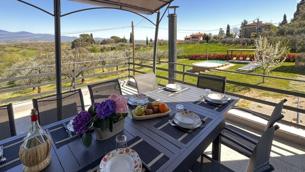 An outdoor dining area with a table set for two, a bottle, and a bowl of fruit. - Awesome home in Marciano della Chiana (Marciano della Chiana)