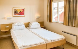 Een tweepersoonskamer met twee bedden, een schilderij aan de muur en een raam met gordijnen.