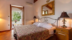 A bedroom with a bed, bedside lamps, a wooden nightstand, a mirror, and a view of a balcony with plants. - Gorgeous home in Koromacno with WiFi (Koromacno)