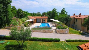 A pool area with a stone patio, lounge chairs, and a small building with a tiled roof. - Gorgeous home in Koromacno with WiFi (Koromacno)