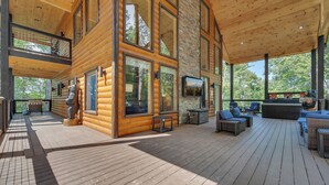 Une cabane en bois spacieuse, dotée d’une terrasse, de grandes fenêtres et d’une cheminée.