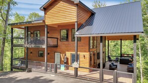 Une cabane en rondins à plusieurs étages, dotée d’une terrasse couverte et d’un espace salon extérieur.