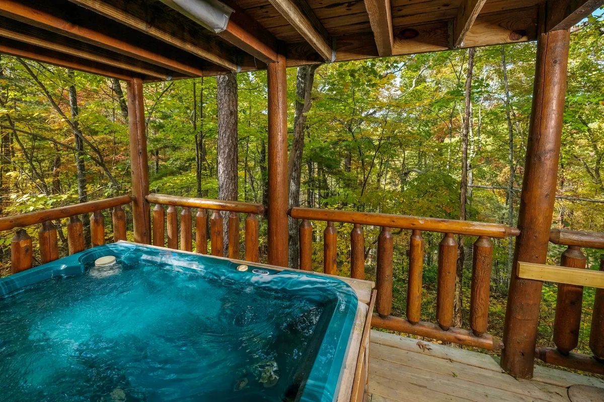 A hot tub on a wooden deck surrounded by trees.