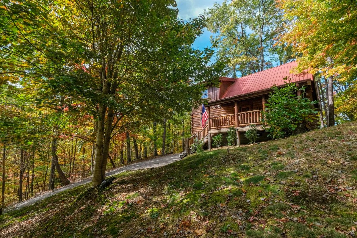 A cabin with a red roof, wooden deck, and a flag.