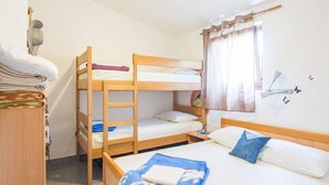 A bunk bed room with a wooden ladder, a desk with folded clothes, and a window with curtains. - 2 bedroom lovely home in Zizanj (Zizanj)