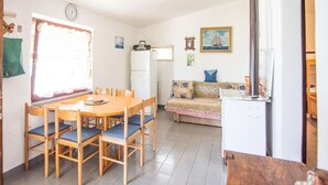 A compact living space with a dining area, a sofa, a refrigerator, and a window with a view. - 2 bedroom lovely home in Zizanj (Zizanj)