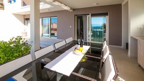 Un balcone con un tavolo in vetro, sedie e una ciotola di frutta.