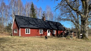 A red wooden house with a black roof, surrounded by trees and a clear sky. - 2 bedroom nice home in Huaröd (Huaröd)