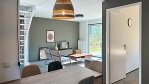 A modern living room with a dining area, a large window, and a view of the outdoors. - 3 bedroom stunning home in Hoeven (Hoeven)