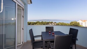 A balcony with a table and chairs, overlooking a coastal view. - Gorgeous apartment in Baska Voda with WiFi (Baska Voda)