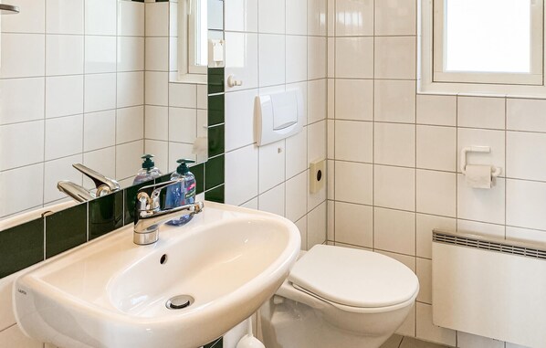 A bathroom with a white sink, a toilet, and a mirror.