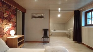 Quarto com cama, cadeira, escrivaninha e banheiro.