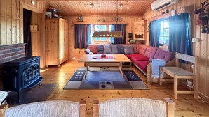A cozy cabin interior with a wooden floor, a sofa, a table, and a fireplace. - Beautiful home in Jordet with sauna (Jordet)