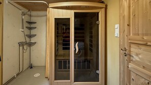 A wooden cabinet with a glass door, a shower area with a glass enclosure, and a wooden door with a handle. - Beautiful home in Jordet with sauna (Jordet)
