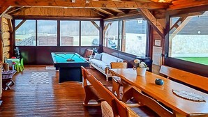Ett mysigt utrymme inomhus med ett biljardbord, träbänkar och en soffa.