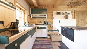 Una cocina compacta con gabinetes de madera, un lavamanos y una estufa. Hay una alfombra tejida de colores en el suelo y una lámpara colgante sobre el lavamanos.