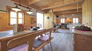 Interior de una cabaña de madera con comedor, cocina y una zona de estar acogedora.