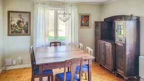Une salle à manger avec une table et des chaises en bois, un buffet et deux tableaux accrochés au mur.