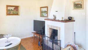 Un salon chaleureux avec une cheminée, un téléviseur et une petite table dont le plateau est en verre.
