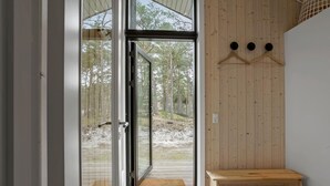 Ein modernes Saunabadezimmer mit Glastüren, die in einen bewaldeten Bereich führen.