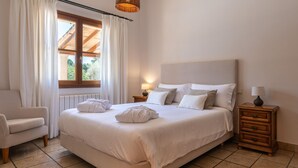 A neatly made bed with white linens, a wooden headboard, and two bedside tables with lamps.