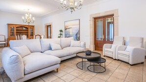 A living room with a sectional sofa, a round coffee table, a white armchair, and a wooden cabinet.