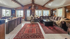 A log cabin interior with a dining area, a sofa, and a fireplace.