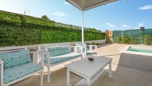 Et udendørs opholdsområde med hvide møbler og en pool.