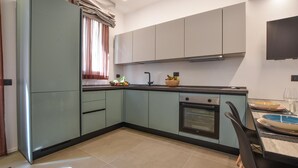 A modern kitchen with light blue cabinets, a built-in oven, and a dining area with a table and chairs. - Stunning apartment in Trappeto with WiFi (Trappeto)