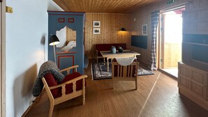 Una stanza accogliente con pareti e soffitto in legno, un divano, un tavolo e una sedia.