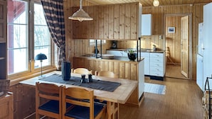 Un interno in legno con zona pranzo, cucina e una scala che conduce in un'altra stanza.