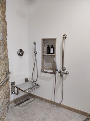 A shower area with a handheld showerhead, a wall-mounted faucet, and a shelf with toiletries. - Casa do Cruzeiro (Ourém)