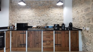 Een keuken met een stenen muur, houten kastjes en een zwart aanrecht.