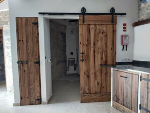 Una habitación con puerta corredera de madera, pared de piedra y suelo de baldosas.