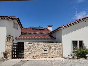 A building with a stone facade, a tiled roof, and a black gate. - Casa do Cruzeiro (Ourém)
