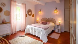 A bedroom with a bed, bedside tables, a dresser, a chair, and a window with curtains.