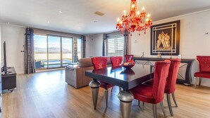 A spacious dining area with a large table and red upholstered chairs, a chandelier, and a view of a pool and mountains through large windows. - Beautiful home in Cox (Cox)