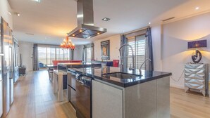A modern kitchen with a central island, stainless steel appliances, and a large window with a view. - Beautiful home in Cox (Cox)