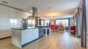A modern kitchen with a central island, stainless steel appliances, and a dining area with red chairs. - Beautiful home in Cox (Cox)
