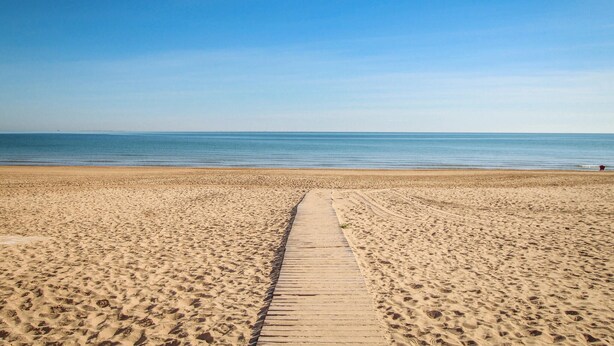 A wide sandy beach with a wooden walkway leading to the water. - Beautiful home in Cox (Cox)
