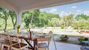 An outdoor dining area with a view of a garden and trees.