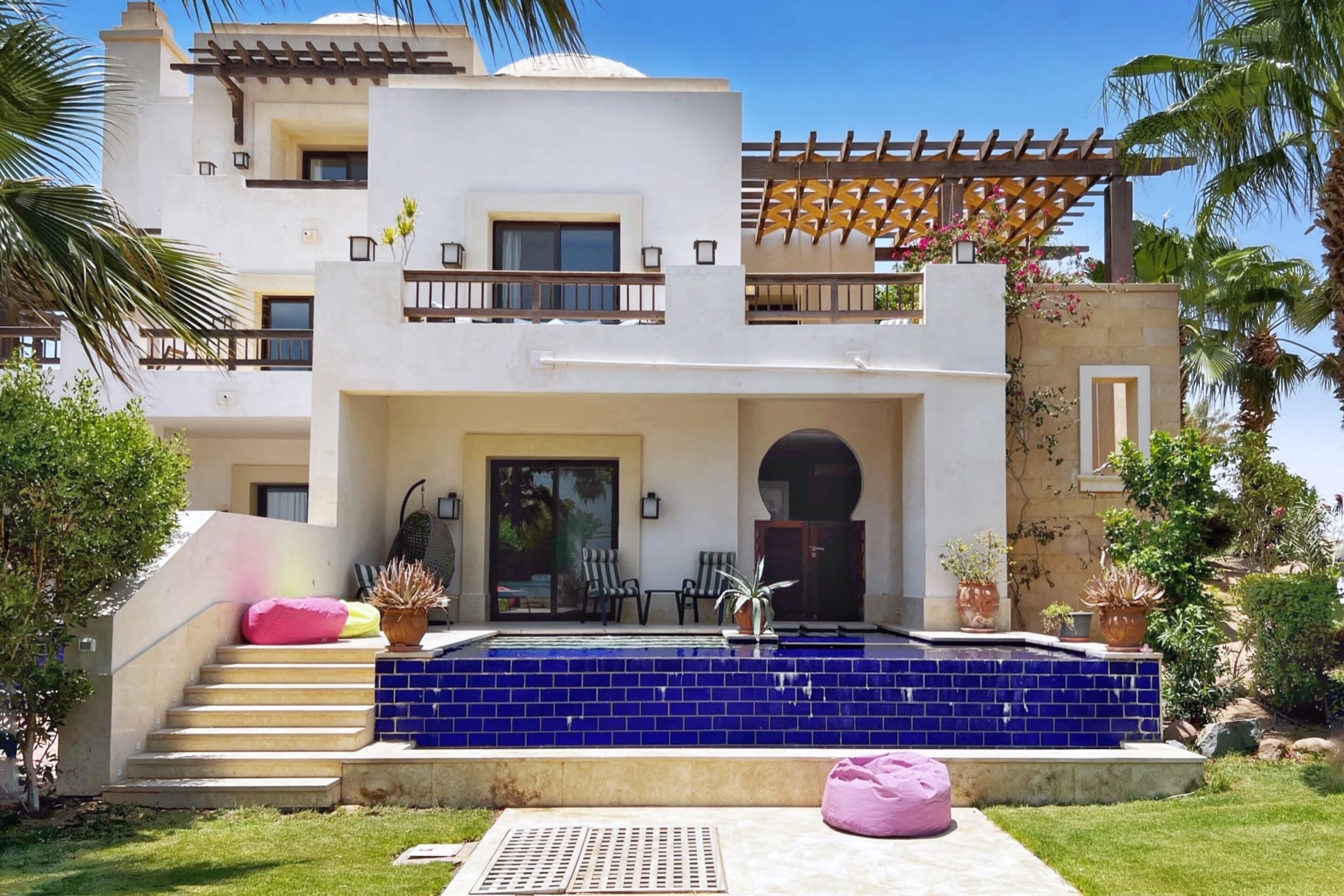 A modern two-story house with a swimming pool, outdoor seating, and a pergola.