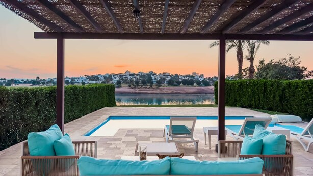 A covered outdoor area with a pool, lounge chairs, and a view of a town in the distance. - Xuru Stays I Sundown Symphony 4mbdr Villa @ Joubal El Gouna (El Gouna)
