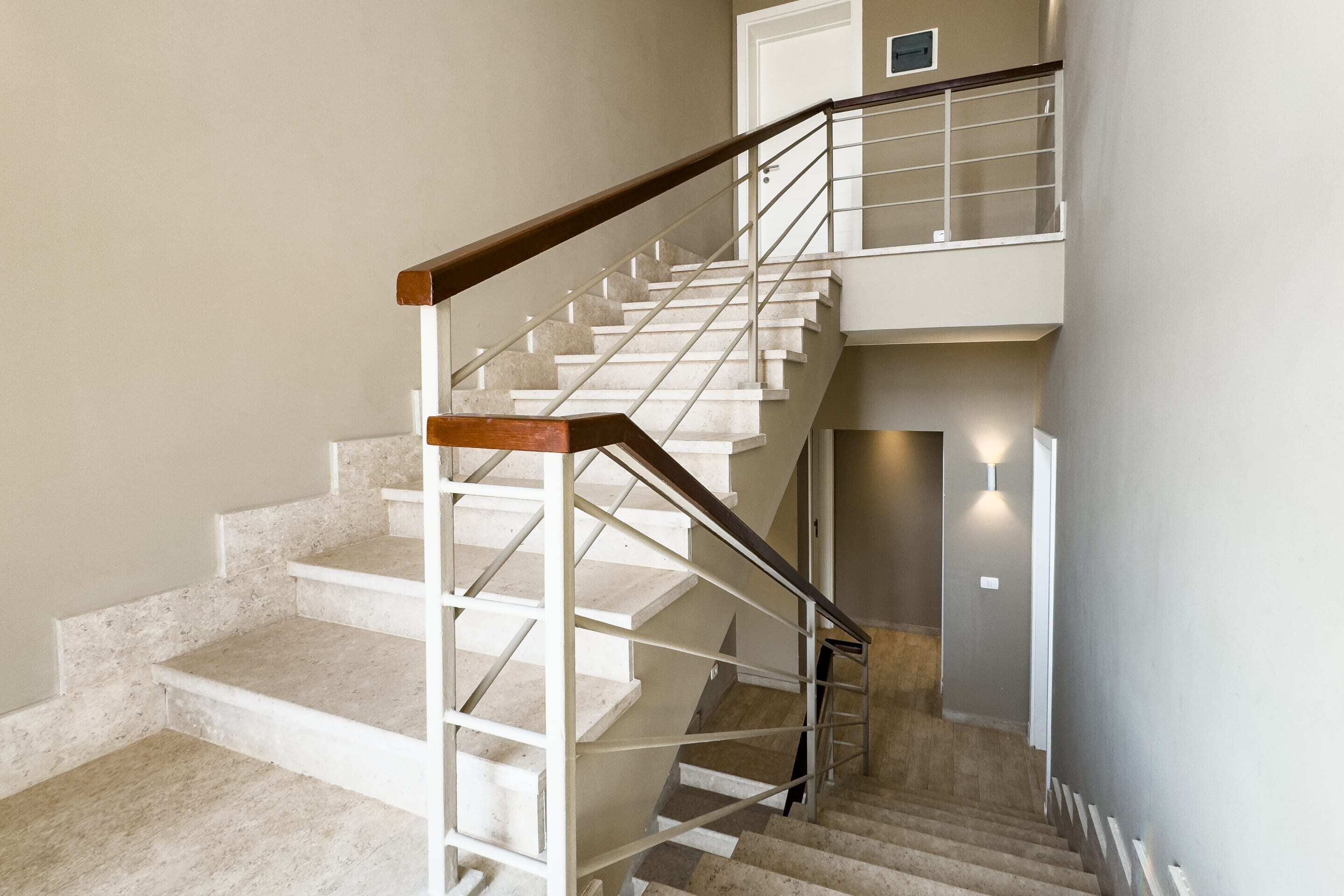 A multi-level staircase with a wooden handrail and metal railings, leading to an upper floor.