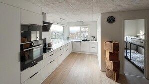 Eine moderne Küche mit weißen Schränken, einem Bosch-Backofen und einem großen Fenster.